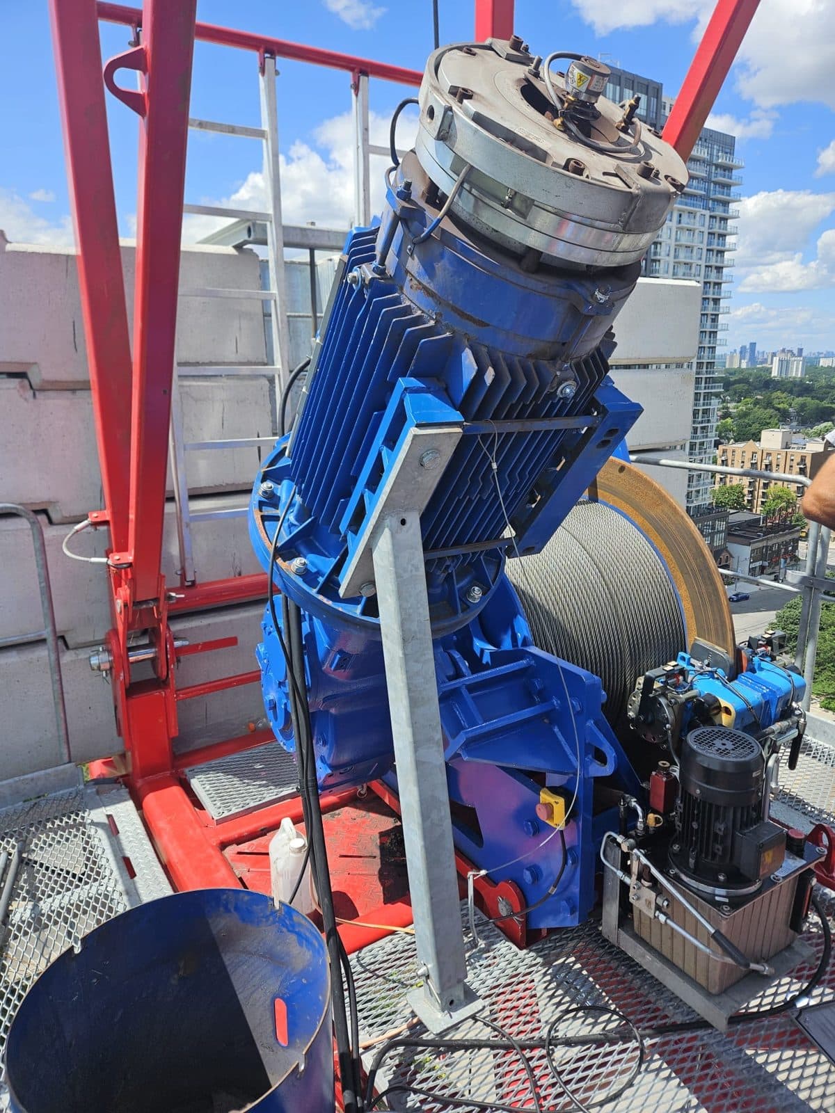 Blue hoist motor and drum on the counter-jib of a red tower crane