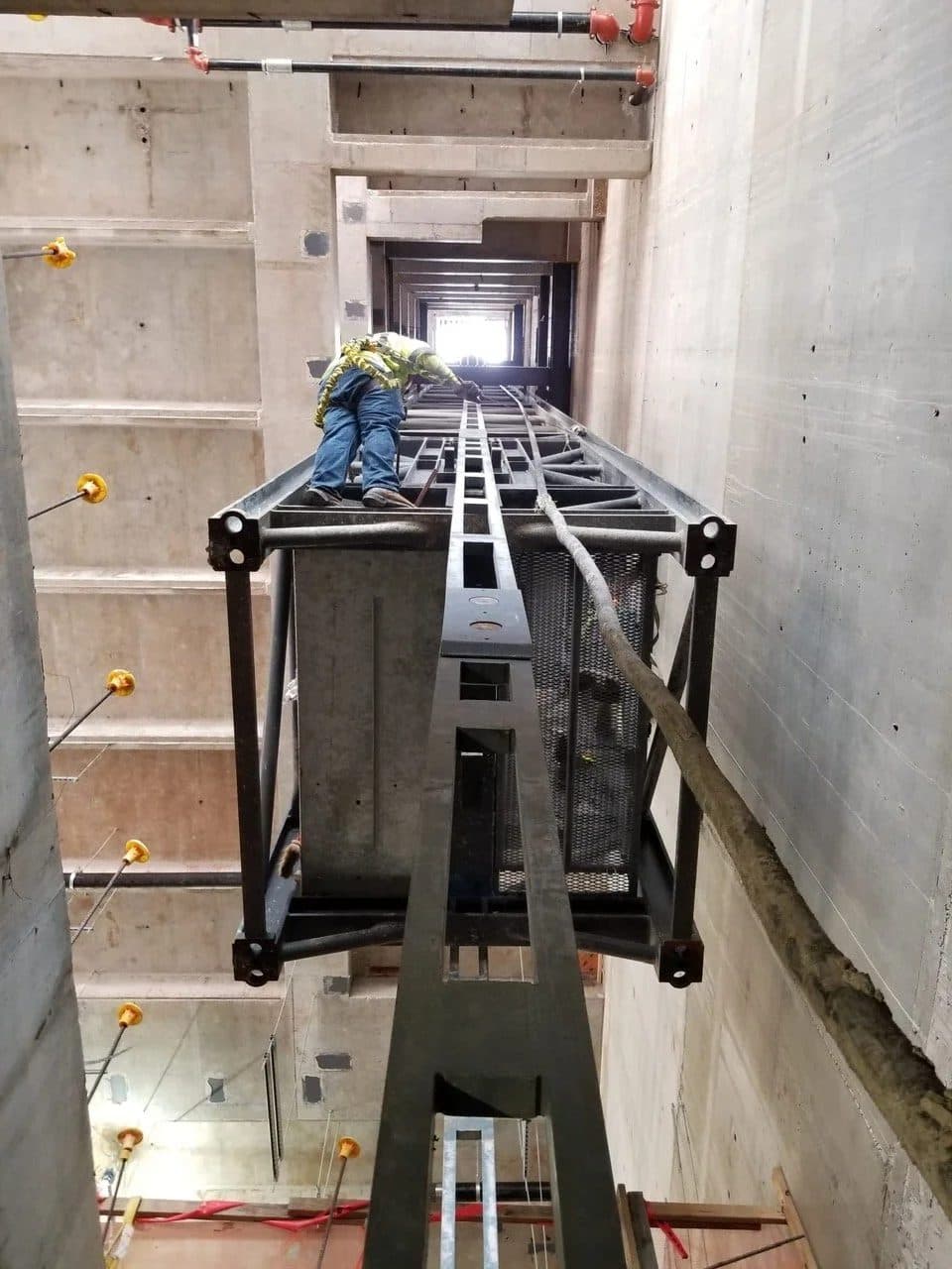 Crew guiding a tower crane mast section through an internal climbing shaft
